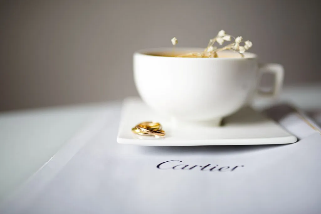 Anillos de oro junto a una taza de café sobre una publicación de Cartier, imagen que representa el legado de Cartier Women’s Initiative y su apoyo al liderazgo femenino.