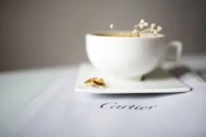 Anillos de oro junto a una taza de café sobre una publicación de Cartier, imagen que representa el legado de Cartier Women’s Initiative y su apoyo al liderazgo femenino.