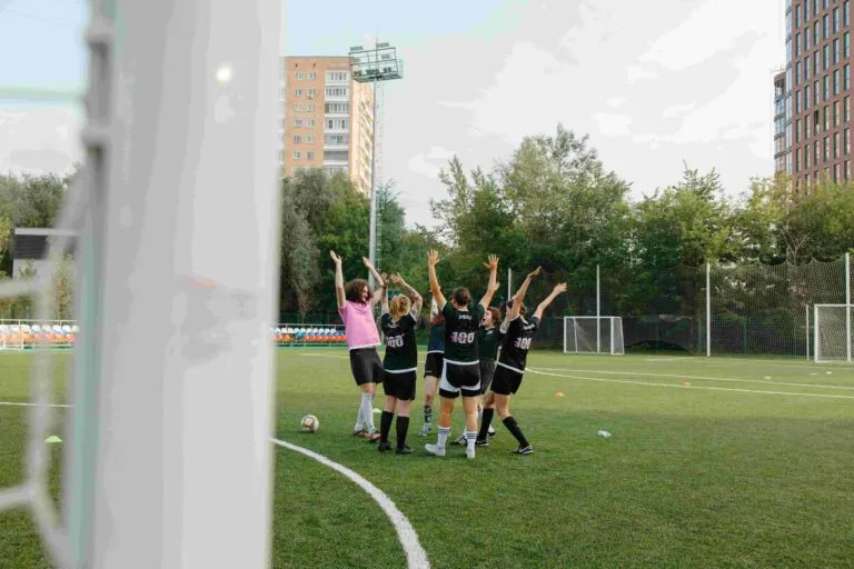 Jugadoras de futbol celebran en equipo durante un entrenamiento en una cancha al aire libre.