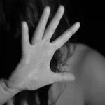 Imagen en blanco y negro de una mujer cubriendo parcialmente su rostro con la mano, utilizada para ilustrar una nota sobre el aumento de las denuncias por violencia sexual y violaciones en España.