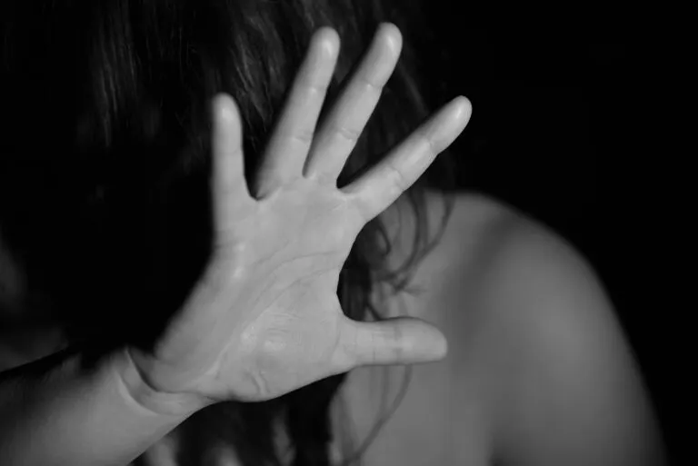 Imagen en blanco y negro de una mujer cubriendo parcialmente su rostro con la mano, utilizada para ilustrar una nota sobre el aumento de las denuncias por violencia sexual y violaciones en España.