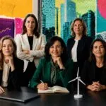 Grupo de mujeres líderes empresariales en una oficina corporativa moderna con indicadores económicos, edificios financieros y elementos relacionados con energía, infraestructura y moda, representando el liderazgo femenino en Europa durante 2026.