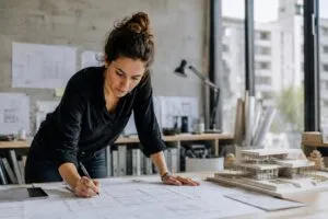Arquitecta desarrolla un proyecto junto a una maqueta arquitectónica moderna en un estudio de diseño contemporáneo.