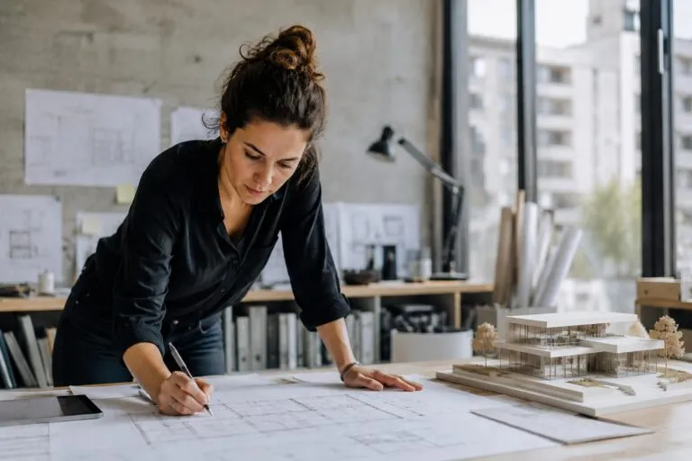 Arquitecta desarrolla un proyecto junto a una maqueta arquitectónica moderna en un estudio de diseño contemporáneo.