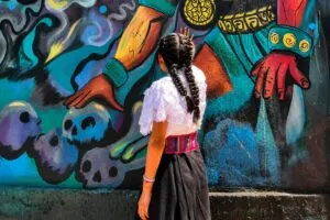 Muralista mexicana trabajando en un mural representativo del muralismo mexicano con enfoque en mujeres artistas e identidad cultural.