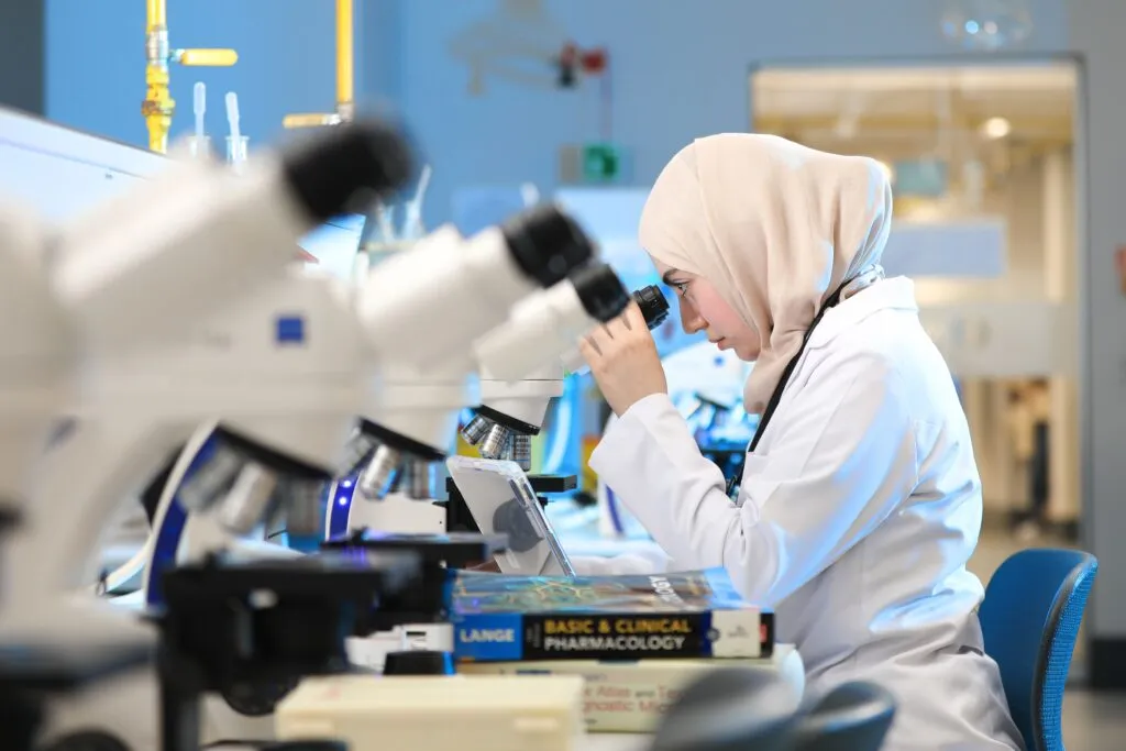 Mujeres en ciencia y tecnología: científica trabaja con un microscopio en un laboratorio.