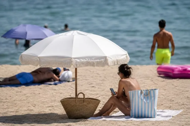 Mujer en una playa observando el mar mientras reflexiona sobre la presión estética y la libertad corporal.