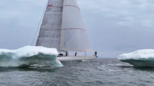 Velero Diablesse de Sailing for Prosperity navega entre dos bloques de hielo con sus velas desplegadas.
