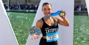 Atleta mexicana corriendo durante una competencia de atletismo con edificios de Chicago al fondo.